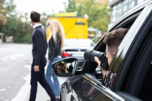 a person sneakily photographing a couple from his car