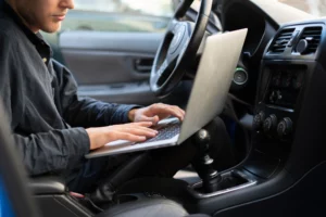 an individual in a vehicle who is using a computer