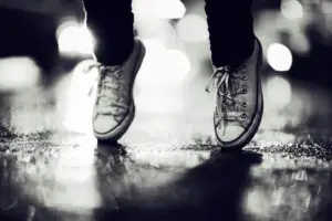 Cropped image of a person wearing sneakers standing on their toes in the street.