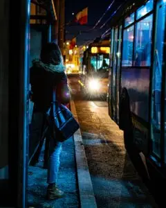 A girl waiting for the bus in the night.