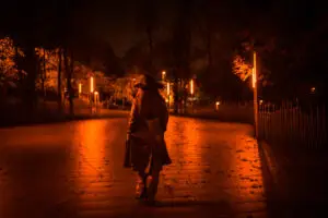 Girl with a hat walking calmly through a park on a winter night